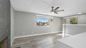 Living room featuring hardwood / wood-style floors, ceiling fan, a fireplace, and a wealth of natural light