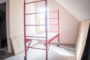 Bonus room with lofted ceiling and wood walls