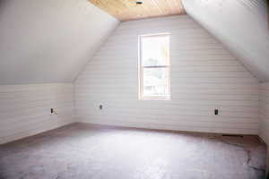 Bonus room with wood ceiling, lofted ceiling, and wooden walls