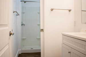 Bathroom with vanity, walk in shower, and wood-type flooring