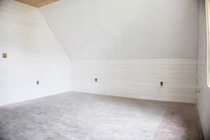 Bonus room with lofted ceiling, concrete flooring, and wood walls