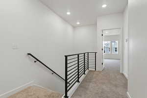 Staircase featuring carpet, baseboards, and recessed lighting