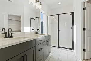 Bathroom featuring marble finish floor, a sink, a shower stall, and double vanity