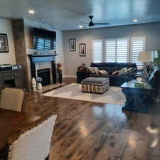 Living room with ceiling fan, a tile fireplace, and dark hardwood / wood-style flooring