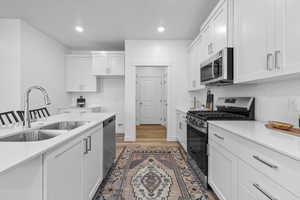 Kitchen featuring white cabinetry, stainless steel appliances, sink, and light wood-type flooring