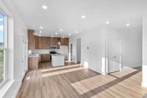 *Photo is of a previously built home of the same layout* Kitchen with light hardwood / wood-style floors, appliances with stainless steel finishes, sink, and a center island