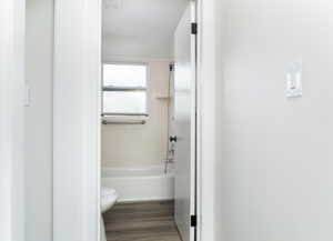 Bathroom featuring toilet, wood-type flooring, and shower / bathtub combination