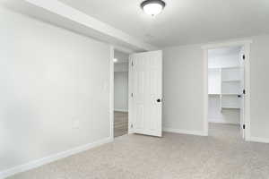 Unfurnished bedroom featuring a closet, a spacious closet, and light colored carpet