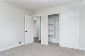 Unfurnished bedroom featuring a closet and light colored carpet