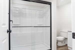 Bathroom featuring vanity, hardwood / wood-style flooring, toilet, and walk in shower