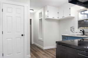 Kitchen with white cabinetry, dark wood-type flooring, sink, and electric range