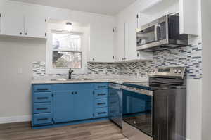 Kitchen featuring white cabinets, hardwood / wood-style flooring, stainless steel appliances, and sink