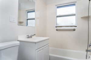 Full bathroom with vanity, toilet, a healthy amount of sunlight, and bathing tub / shower combination