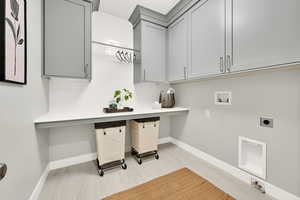 Laundry room with hookup for an electric dryer, light hardwood / wood-style floors, washer hookup, and cabinets