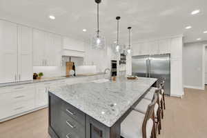 Kitchen featuring a spacious island, sink, white cabinets, and light hardwood / wood-style flooring