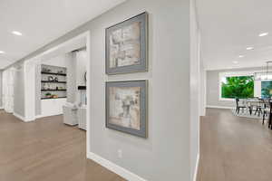 Hall with light hardwood / wood-style floors and built in shelves