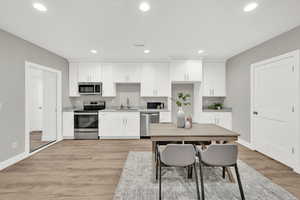 Kitchen featuring appliances with stainless steel finishes, white cabinetry, sink, and light wood-type flooring