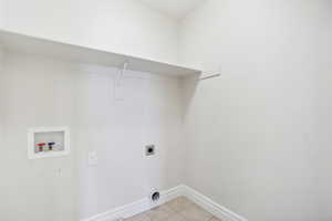 Laundry room with hookup for a washing machine, electric dryer hookup, and light tile patterned flooring