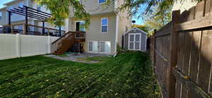 Back of property with a large Shed, a wooden deck, and a lawn