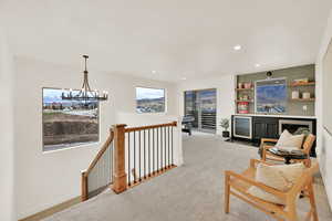 Loft area with wine cooler, a notable chandelier, wet bar, and light carpet