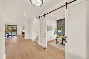 Hallway with light hardwood / wood-style flooring and a barn door