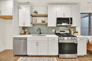 Kitchen featuring light hardwood / wood-style floors, white cabinetry, and stainless steel appliances