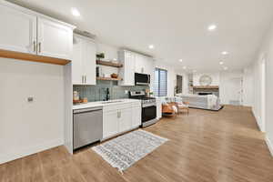 Kitchen with white cabinets, stainless steel appliances, and light wood-type flooring