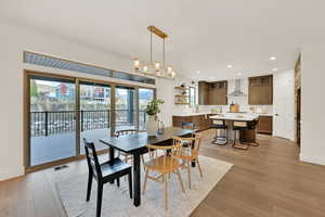 Dining space with light hardwood / wood-style flooring and an inviting chandelier