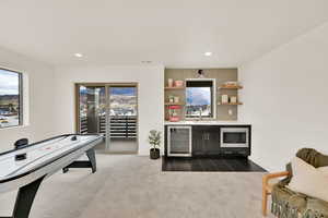 Recreation room with wet bar, wine cooler, and dark colored carpet