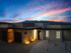 Back house at dusk featuring a mountain view and a patio area