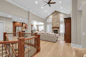 Living room with light hardwood / wood-style floors, a healthy amount of sunlight, high vaulted ceiling, and a stone fireplace