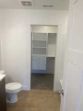 Bathroom with vanity, hardwood / wood-style floors, toilet, and a tub to relax in