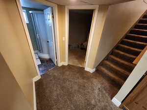 Hallway featuring dark colored carpet