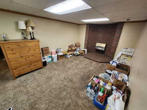 Basement featuring ornamental molding, a drop ceiling, carpet floors, and a brick fireplace