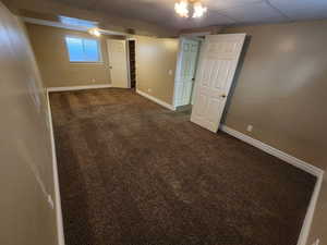 Basement with a paneled ceiling and dark carpet