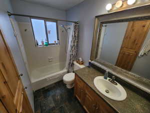 Full bathroom featuring shower / bath combination with curtain, vanity, and toilet