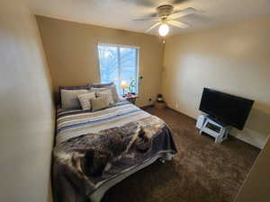 Bedroom featuring dark carpet, ceiling fan, and a textured ceiling