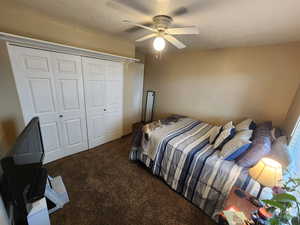 Carpeted bedroom with a textured ceiling, a closet, and ceiling fan