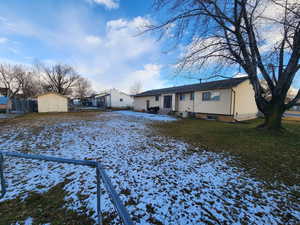 View of front of house featuring a lawn and a storage shed