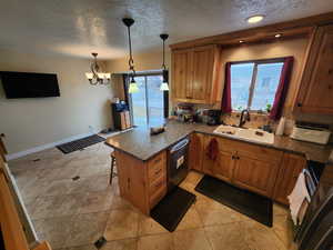 Kitchen featuring a kitchen breakfast bar, dishwasher, pendant lighting, sink, and kitchen peninsula