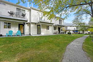 Rear view of property with a balcony, a yard, and a patio