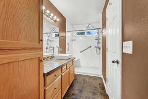 Bathroom with vanity and tiled shower