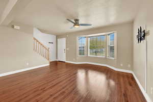 Unfurnished living room with ceiling fan, dark hardwood / wood-style flooring, and a textured ceiling