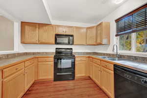 Kitchen with light brown cabinets, sink, light hardwood / wood-style flooring, and black appliances