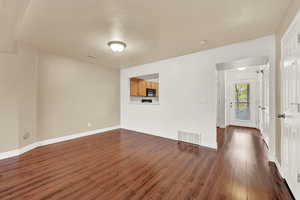 Unfurnished living room with a textured ceiling and dark hardwood / wood-style floors