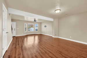 Empty room with a textured ceiling, ceiling fan, and dark wood-type flooring