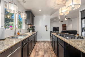 Kitchen featuring lofted ceiling, light hardwood / wood-style flooring, sink, pendant lighting, and tasteful backsplash