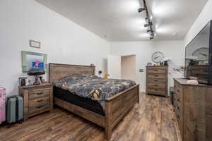 Bedroom featuring a textured ceiling, track lighting, and dark hardwood / wood-style flooring