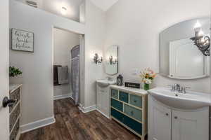 Bathroom with vanity, hardwood / wood-style flooring, and a towering ceiling