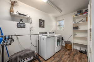 Washroom with dark wood-type flooring and washer and dryer